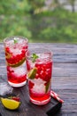 Refreshing drink, lemonade with red currant, lime and ice cubes in glasses on a dark wooden background Royalty Free Stock Photo