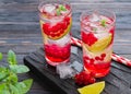 Refreshing drink, lemonade with red currant, lime and ice cubes in glasses on a dark wooden background Royalty Free Stock Photo