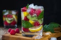 Refreshing drink with mineral water, with berries and fruits raspberry, lemon, kiwi and ice on a black background.