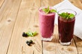 Refreshing drinks in glass glasses. Milkshake and smoothie. Blackcurrant berries and green leaves on wooden background