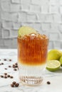 Refreshing espresso tonic drink with slice of lime and coffee beans on white marble table Royalty Free Stock Photo