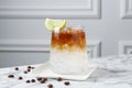 Refreshing espresso tonic drink with slice of lime and coffee beans on white marble table Royalty Free Stock Photo