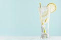 Refreshing fitness cold mineral beverage with lemon slices, ice cubes, sparkling water, yellow straw in misted glass in modern. Royalty Free Stock Photo