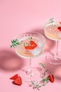 refreshing fruit cocktail or punch with wine champagne, strawberries, ice and rosemary on pink background. Freeze motion splash