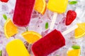 Refreshing fruit popsicle lollies on ice background with berries, peppermint.