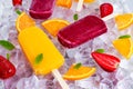 Refreshing fruit popsicle lollies on ice background with berries, peppermint.