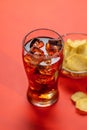 Refreshing glass of cola with ice, accompanied by a serving of crispy chips