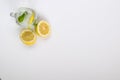 A Refreshing Glass of Lemon Water with Mint leaves and Halved Lemons resting Beside the Glass