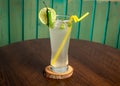 refreshing glass of Spicy Lemonade with lime slice, green chili and straw isolated on wooden table side view ramdan drink