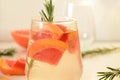 Refreshing grapefruit cocktail with ice and rosemary on a white background. rosemary on the table. or detox water or Royalty Free Stock Photo