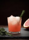 Refreshing grapefruit cocktail with rosemary on dark background.