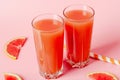 Refreshing grapefruit juice with straws on a pink background with grapefruit slices. Summer refreshing diet drink Royalty Free Stock Photo