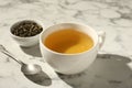 Refreshing green tea in cup, dry leaves and spoon on white marble table, closeup Royalty Free Stock Photo