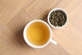 Refreshing green tea in cup and dry leaves on wooden table, top view Royalty Free Stock Photo