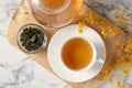 Refreshing green tea and dry leaves on white marble table, flat lay Royalty Free Stock Photo