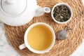 Refreshing green tea, strainer and dry leaves on white marble table, top view Royalty Free Stock Photo