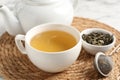 Refreshing green tea, strainer and dry leaves on white table, closeup Royalty Free Stock Photo