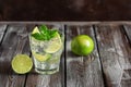 Refreshing homemade lemonade in a glass with lime, mint leaves and ice on a dark wooden table. Selective focus Royalty Free Stock Photo