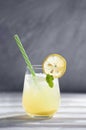 Refreshing iced lemonade with juice in the glass with sliced lemon decoration, mint leaves and green straw