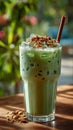 Refreshing iced matcha latte with crushed nuts garnish in sunlit cafe setting Royalty Free Stock Photo