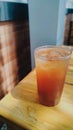 Refreshing iced tea served in a plastic cup with condensation, placed on a wooden table in natural light Royalty Free Stock Photo