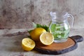 Refreshing lemonade in a beautiful decanter, lemons, fragrant sprigs of mint on the table.