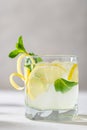 Refreshing lemonade with lemon, mint, ginger and ice in glass and bottle on white concrete background. Summer refreshing drink. Royalty Free Stock Photo