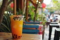 Refreshing mango bubble tea standing on wooden table in outdoor cafe Royalty Free Stock Photo