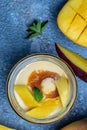 Refreshing mango ice cream with mint leaves and fresh mango served in a glass jar. vertical image. top view. place for text Royalty Free Stock Photo