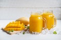 Refreshing mango smoothies in glass with ripe mango