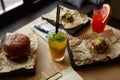 Refreshing mojito cocktail, hamburgers and tapas snacks served on decorative parchement paper and wooden plates in a restaurant. Royalty Free Stock Photo