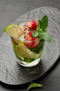 Refreshing mojito cocktail with lime, mint, strawberry, and ice on dark background Royalty Free Stock Photo