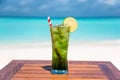 Refreshing mojito mocktail with straw on wooden table ocean background at the beach