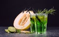 Refreshing non-alcohol drinks. Cut melon and green cocktails on a black background. Sweet drinks with liquor, lime and tarragon. Royalty Free Stock Photo