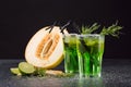 Refreshing non-alcohol drinks. Cut melon and green cocktails on a black background. Sweet drinks with liquor, lime and tarragon. Royalty Free Stock Photo