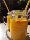 Refreshing orange juice in a jar together with a straw and with slices of fresh orages