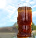 Refreshing orange summer cocktails with cola and ice against a blue sky background. Close up view