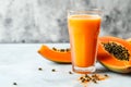 Refreshing papaya smoothie on light grey background with copy space. Glass of smooth papaya juice with seeds and fresh papaya Royalty Free Stock Photo