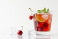 Refreshing red cocktail with sparkling water and ice garnished with a lime and cherry Royalty Free Stock Photo