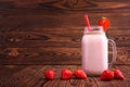 A refreshing strawberry smoothie in a big mason jar with red straw and decorative strawberry on the wooden background. Copy space. Royalty Free Stock Photo