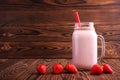 A refreshing strawberry smoothie in a big transparent jar with red straw and berries on the wooden background. Copy space. Royalty Free Stock Photo