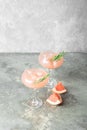 Refreshing summer cocktail of grapefruit juice of rosemary and ice in two glass glasses on gray background of concrete. Royalty Free Stock Photo