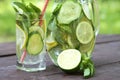 Refreshing summer cold drinks Sassy water with lemon, lime, cucumber, mint, ginger in glass and jug on wooden table, outdoor. Royalty Free Stock Photo