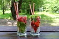 Refreshing summer cold drinks Strawberry with lemon, lime, cucumber, mint, ginger in glass and jug on wooden table, outdoor.