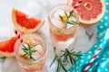 Refreshing summer drink with grapefruit and rosemary on a stone background.