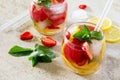 A refreshing summer drink with ice and strawberries on a stone background.