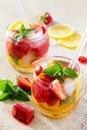 A refreshing summer drink with ice and strawberries on a stone background.