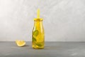 Refreshing summer drink with lemon, honey and mint. Yellow transparent glass bottle on grey background.  Space for your text Royalty Free Stock Photo