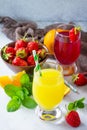 Refreshing summer drinks assortment. Orange juice, strawberry juice, fresh oranges and strawberries on a gray stone or slate Royalty Free Stock Photo