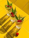 Refreshing summer drinks in crystal glasses green leaves raspberry on yellow tile background Sweet cold natural cocktail Royalty Free Stock Photo